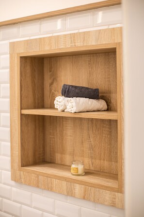 A wooden shelf unit with folded towels and a candle.