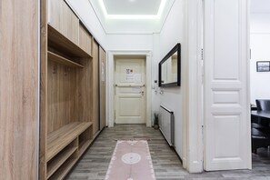 A hallway with wooden lockers, a white door, a radiator, and a mirror on the wall.