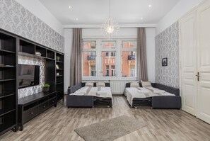 Una habitación moderna con dos camas, un televisor y un amplio ventanal con vistas a edificios.