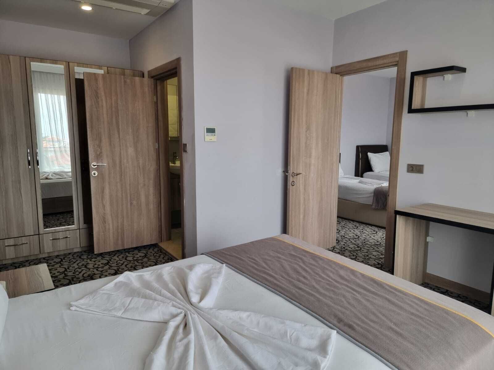 A hotel room with a bed, a wardrobe, a mirror, and a small desk.