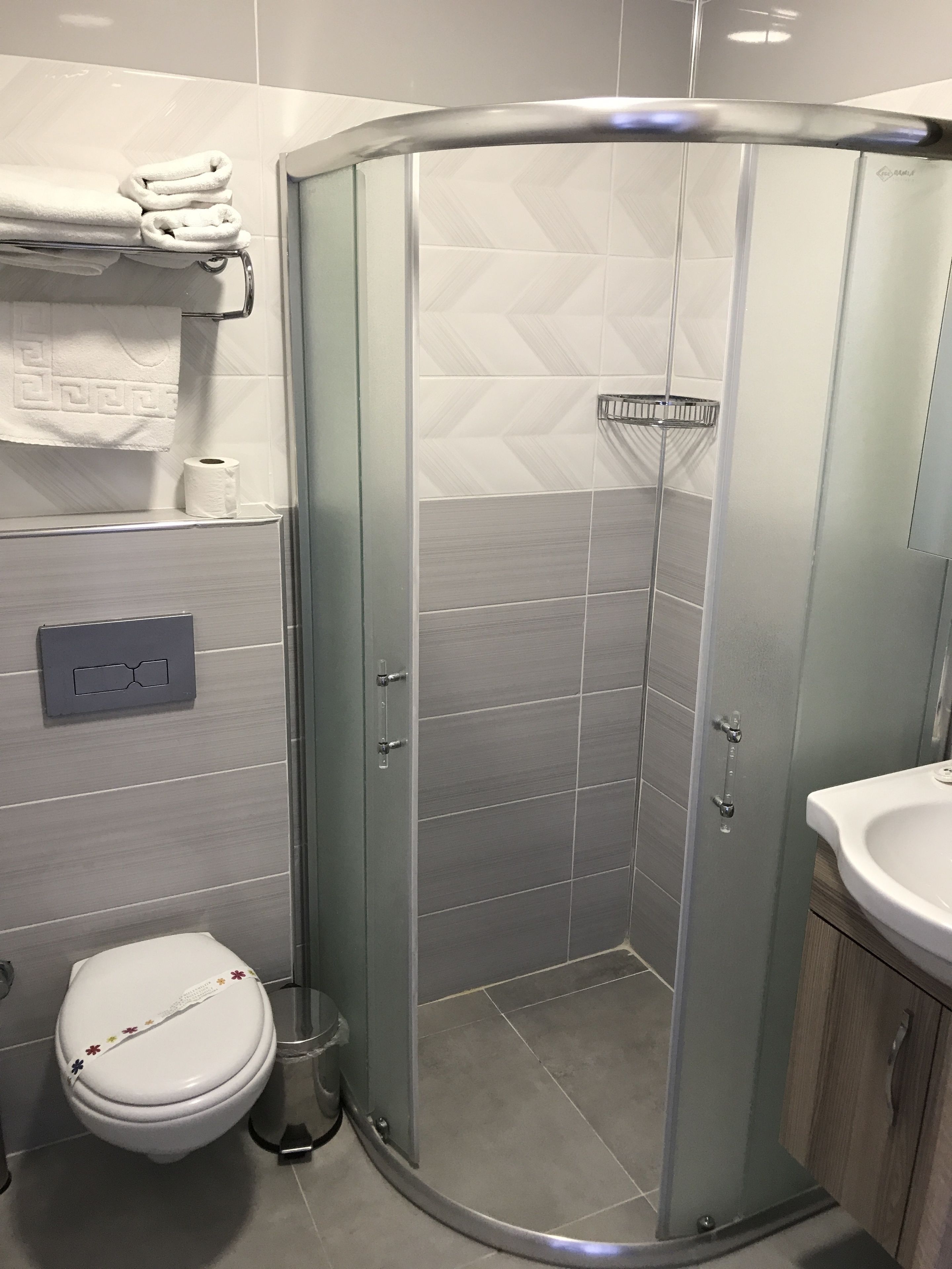 Un baño moderno con cabina de ducha de vidrio, inodoro y lavabo.