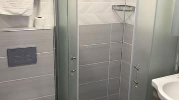 Un baño moderno con cabina de ducha de vidrio, inodoro y lavabo.