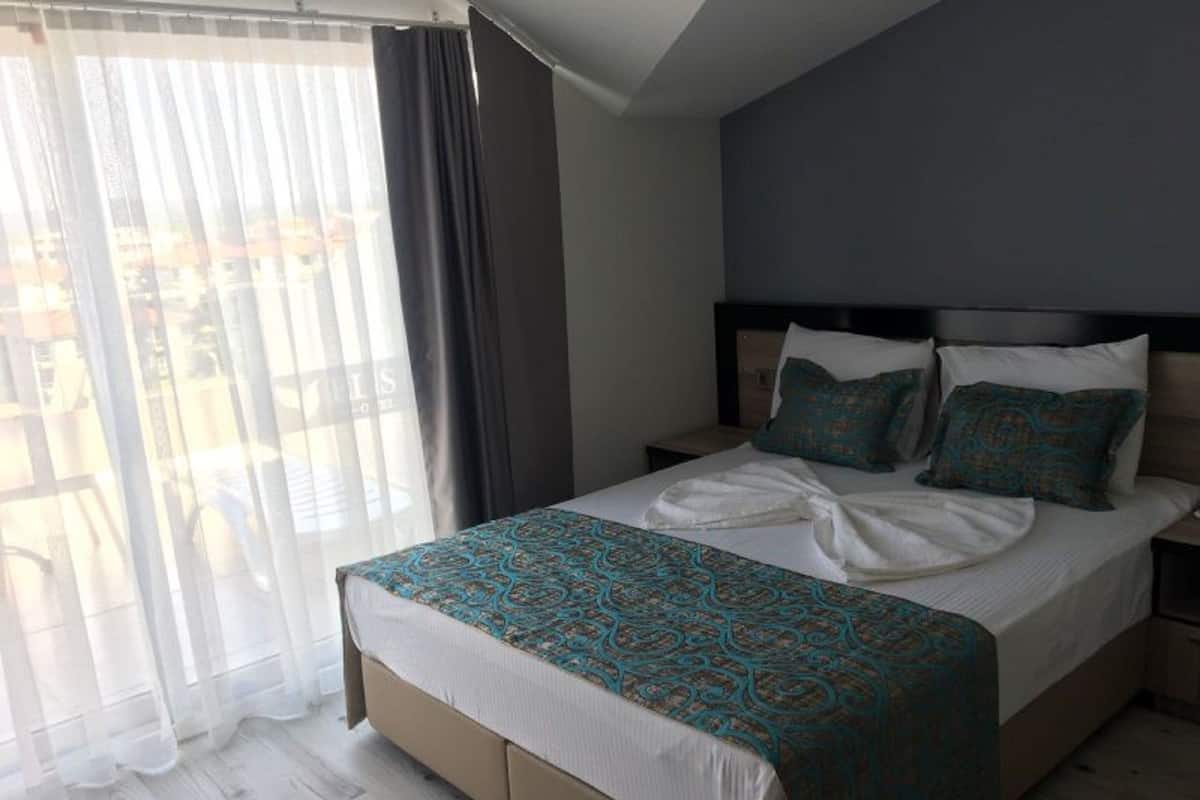 A bedroom with a bed, a nightstand, and a window with curtains.