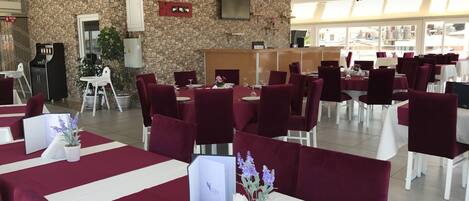 Un ristorante con pareti in pietra, sedie in velluto rosso e tovaglie bianche.