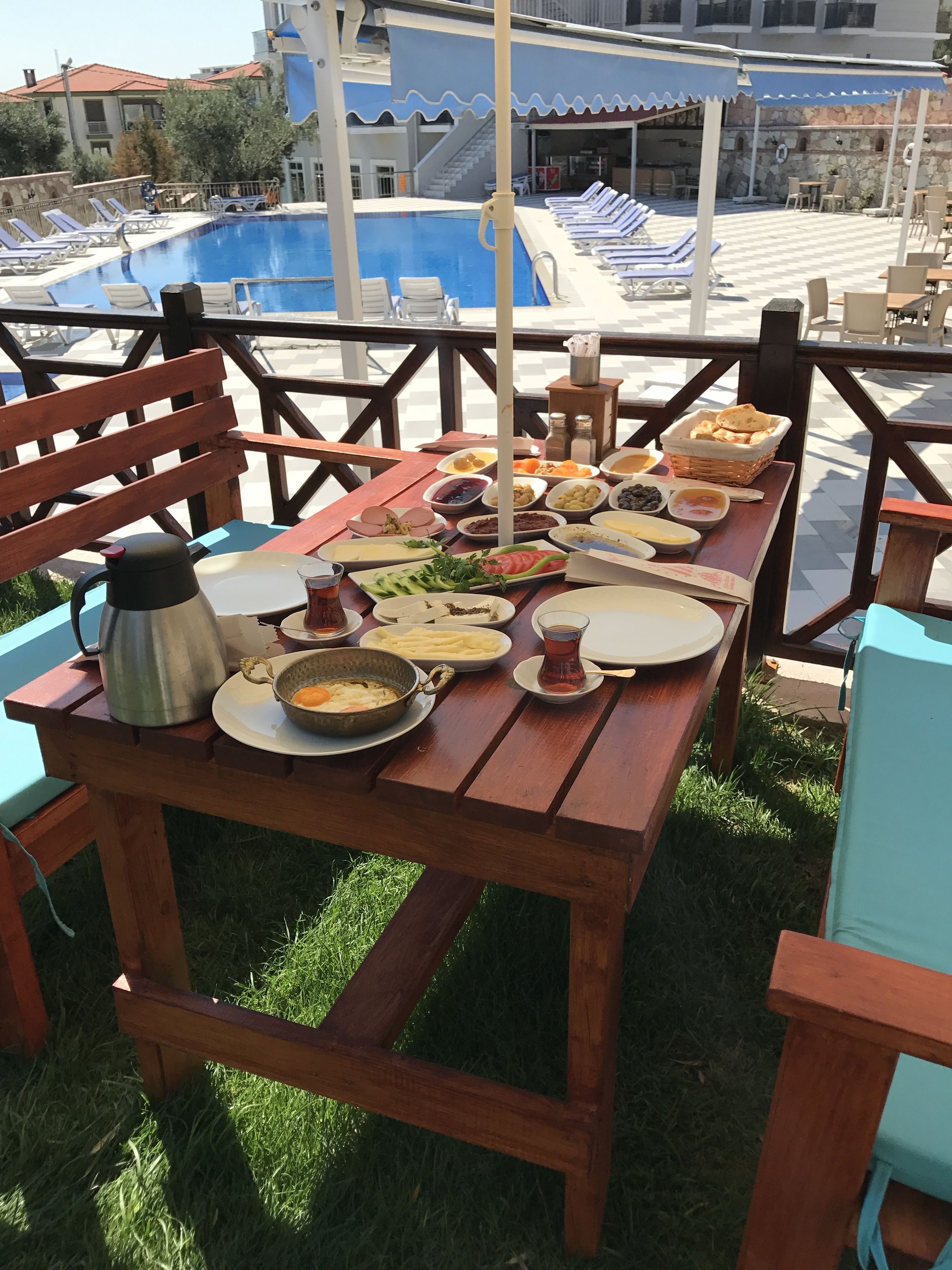 Un área de comedor al aire libre con una piscina de fondo.