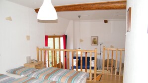 A room with a bed, a wooden bench, a small table, and a window with curtains. - Maison Neuve Grandval - Gite (Grandval)