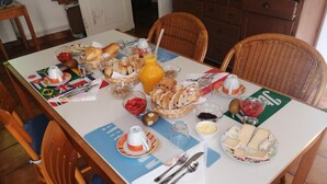 A dining table set with various breakfast items including bread, fruits, cheese, and beverages. - Maison Neuve Grandval - Gite (Grandval)