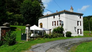 A white building with a chimney, a white door, and a small window. - Maison Neuve Grandval - Gite (Grandval)