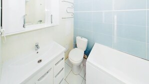 Une salle de bain avec un lavabo blanc, un miroir, des toilettes et une baignoire.