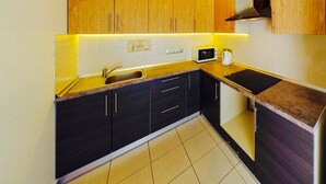 Une cuisine de taille réduite, dotée de meubles en bois, d’un four à micro-ondes et d’un évier.