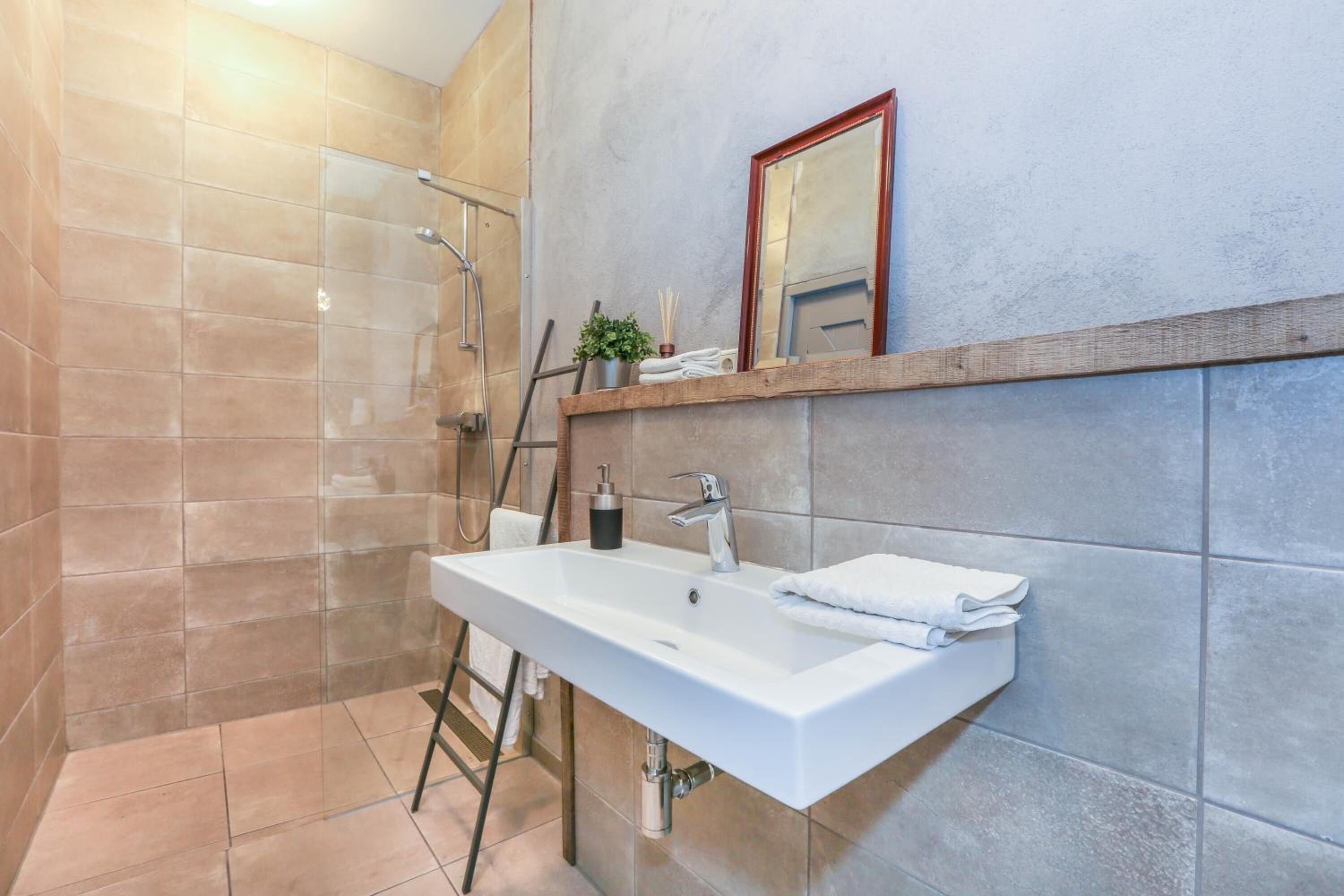 A modern bathroom with a large sink, a mirror, and a shower area.