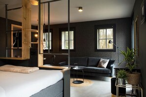 A modern bedroom with a bed, a sofa, a small table, and a mirror. - B&B Adelaerthoeve (Arnhem)