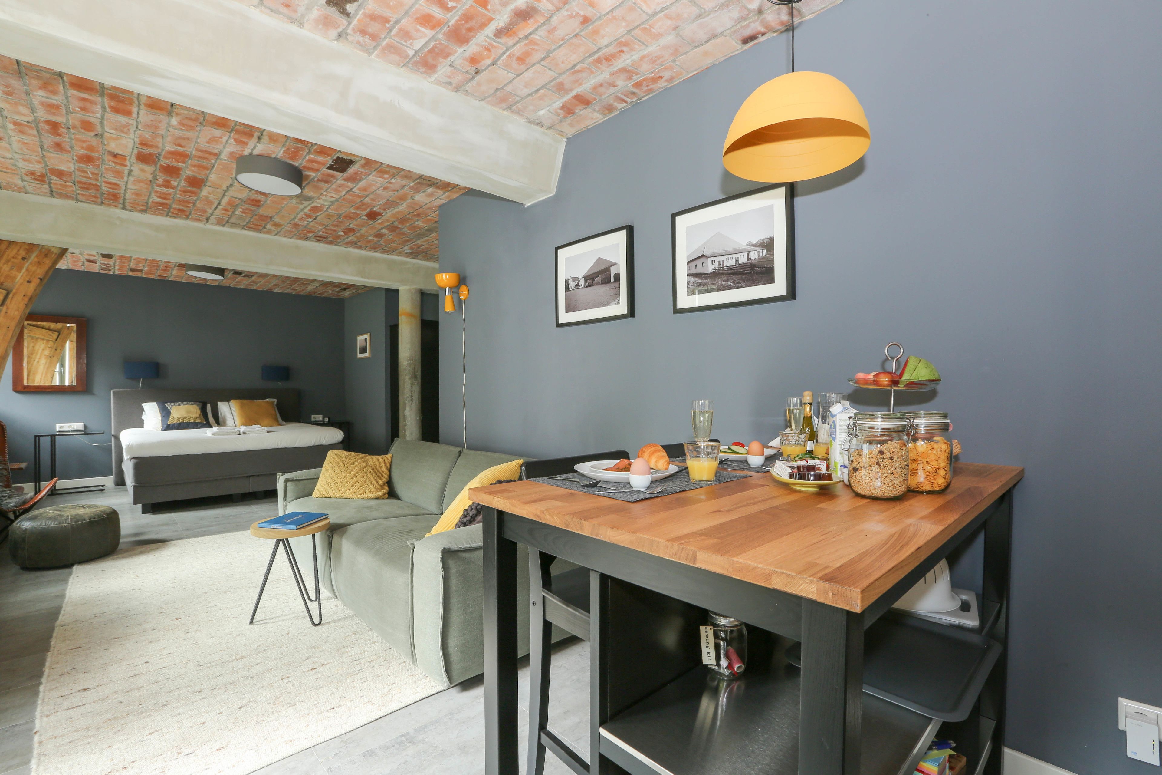A modern living space with a dining area, a bed, and a kitchenette.