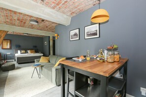 Um espaço de estar moderno com área de jantar, cama e cozinha compacta.