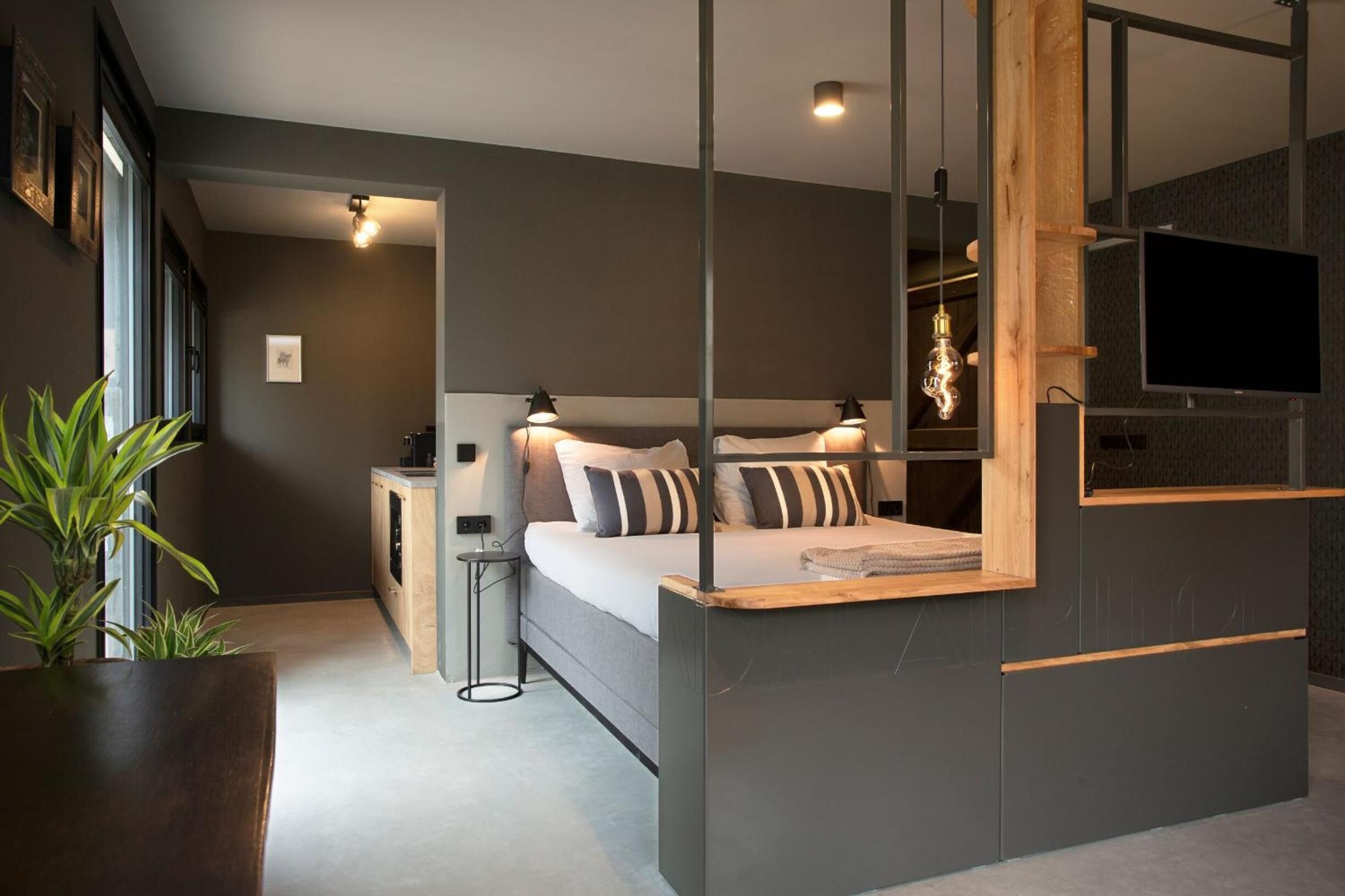 A modern bedroom with a bed, bedside tables, a TV, and a large mirror.