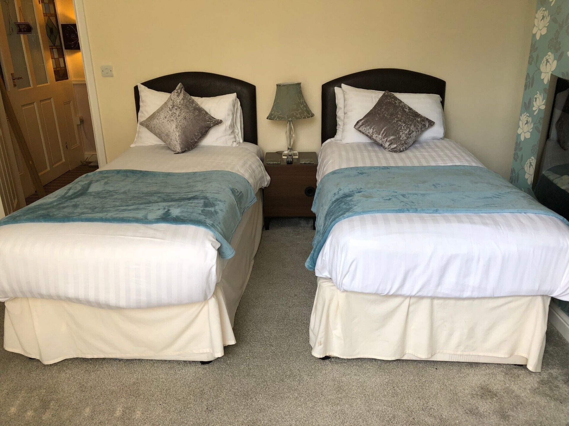 A twin bedroom with two beds, each with a pillow and a blue blanket.