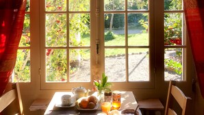 A breakfast table with a variety of food items and a view of a garden through a window. - Villa du Parc (Prades)