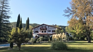 A traditional chalet-style building with a balcony, surrounded by a well-maintained lawn and trees. - Villa du Parc (Prades)