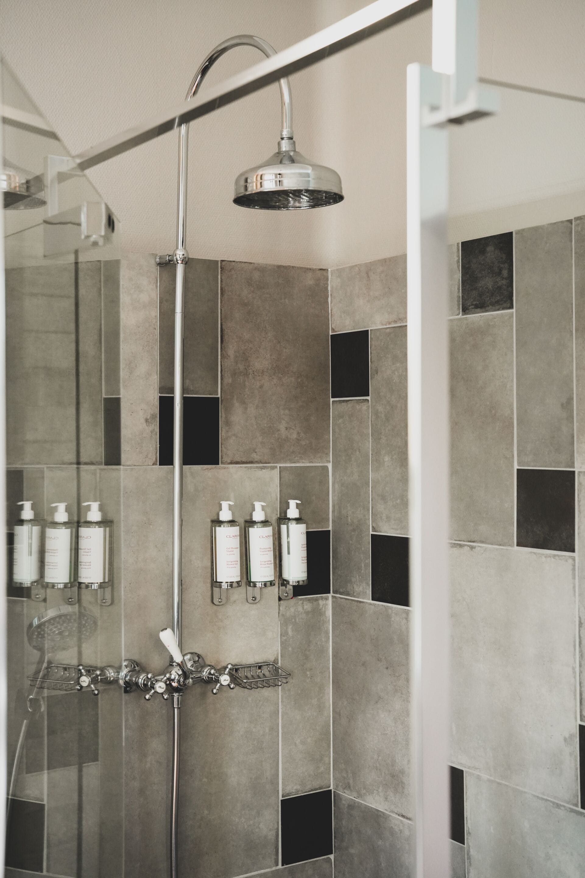 A shower with a rain showerhead, a handheld showerhead, and a glass-enclosed shower area.