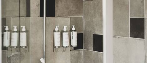 A shower with a rain showerhead, a handheld showerhead, and a glass-enclosed shower area.