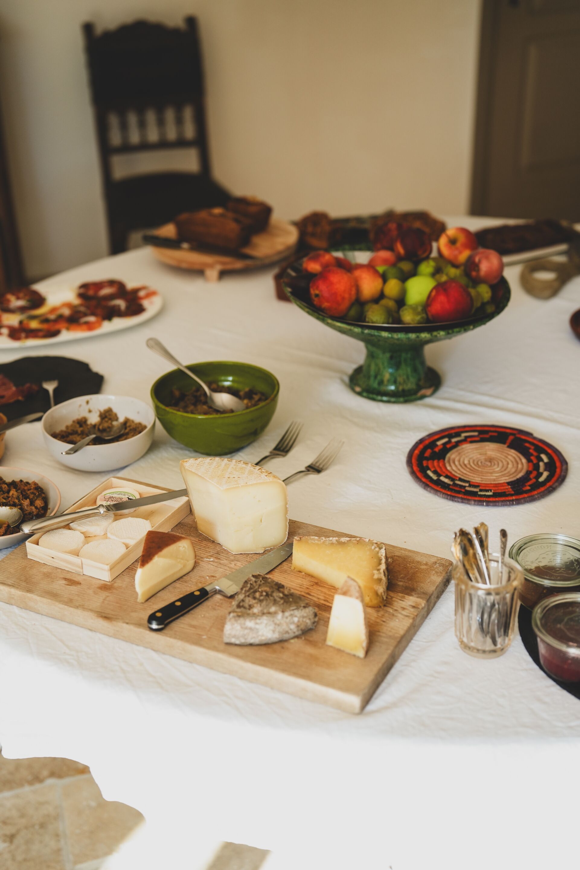 A table with various cheeses, fruits, and condiments.