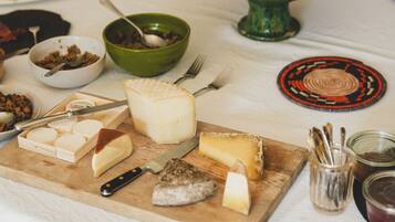 A table with various cheeses, fruits, and condiments.