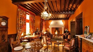 A traditional dining room with a fireplace, wooden furniture, and a chandelier. - Manoir de la Malartrie (Vezac)