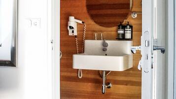 A bathroom with a wooden vanity, a sink, a mirror, and a hairdryer.