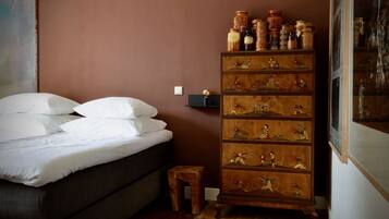 Un dormitorio con una cama, un aparador de madera con adornos y un taburete pequeño.