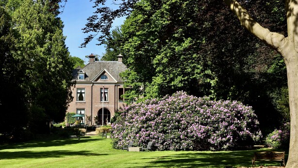 A large brick building with a symmetrical facade, surrounded by lush greenery and a well-maintained lawn. - Hotel De Lochemse Berg (Barchem)