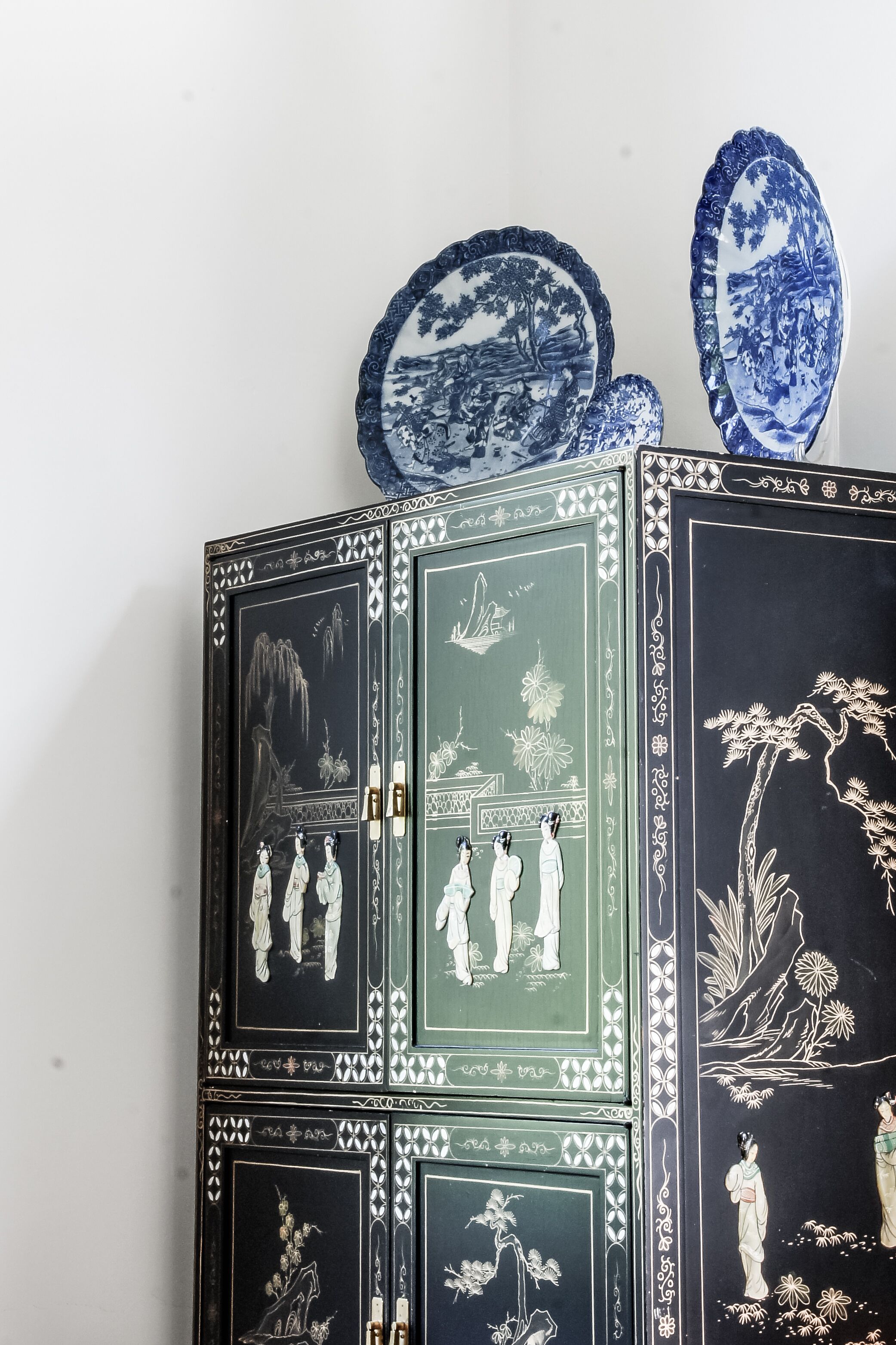 Un meuble orné de motifs et de sculptures complexes, surmonté de deux assiettes bleues et blanches.