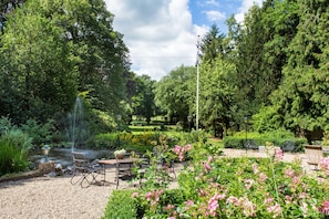 A garden with a pond, seating area, and a flagpole. - Hotel De Lochemse Berg (Barchem)