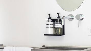 A bathroom with a rectangular sink, a mirror, and two gold dragonfly wall decorations.