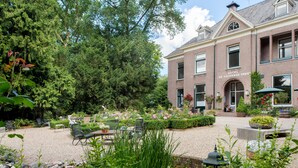 A hotel with a garden patio, outdoor seating, and a pond. - Hotel De Lochemse Berg (Barchem)