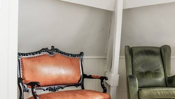 A room with a brown leather armchair, a green leather armchair, and a coffee table with a stack of books.