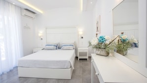 A modern bedroom with a large bed, bedside tables, a mirror, and a decorative plant. - White Passion Villa (Rhodes)