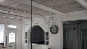 A modern kitchen with white cabinetry, a dining area with a round table and white chairs, and a wooden ceiling. - White Passion Villa (Rhodes)