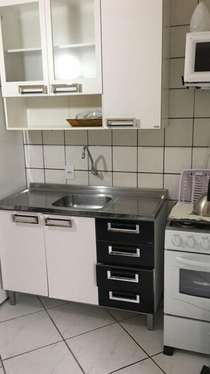 Een koelkast, een microgolfoven, een oven, kookgerei, borden en bestek