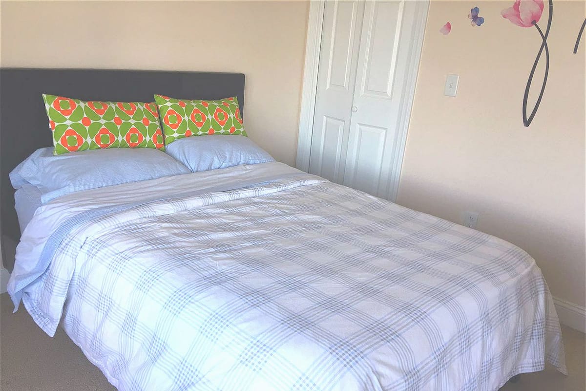 A neatly made bed with a plaid bedspread and two pillows with a geometric pattern.