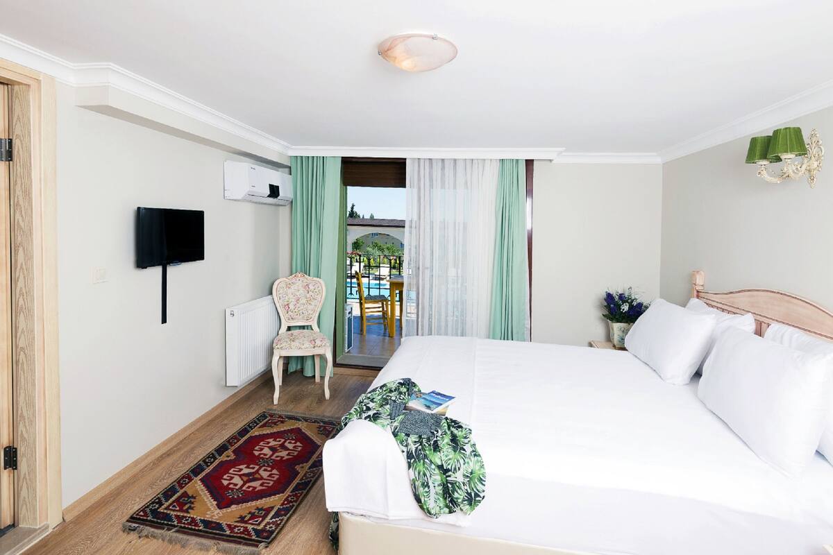 A hotel room with a large bed, a television mounted on the wall, a chair, and a view through a doorway.