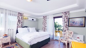 A bedroom with a bed, a chair, a small table, and a window with curtains. - Belizi Hotel (Urla)