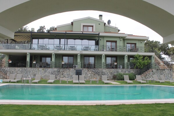 A large building with a swimming pool, multiple balconies, and outdoor seating areas. - Belizi Hotel (Urla)