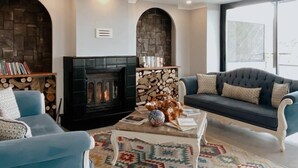 A living room with a fireplace, blue sofas, a coffee table, and a patterned rug. - Belizi Hotel (Urla)