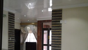 A hallway with a tiled floor, a door with a window, and a wall with a patterned design. - Channel View Lodge (Kempton Park)