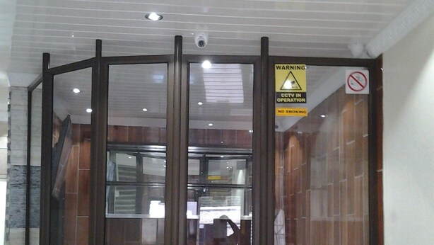 A hotel entrance with a glass door, a warning sign about CCTV, and a no smoking sign. - Channel View Lodge (Kempton Park)