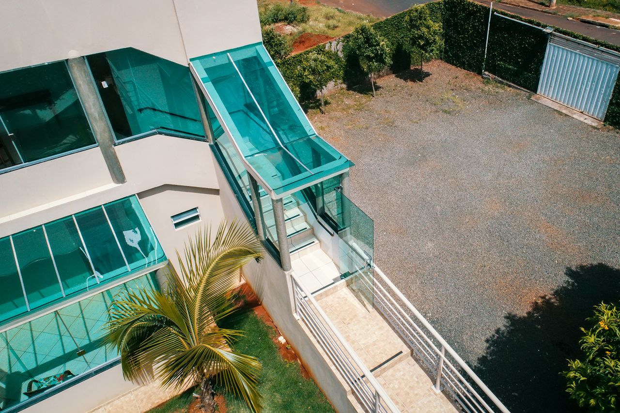 A modern building with large glass windows and a small outdoor area with a palm tree.
