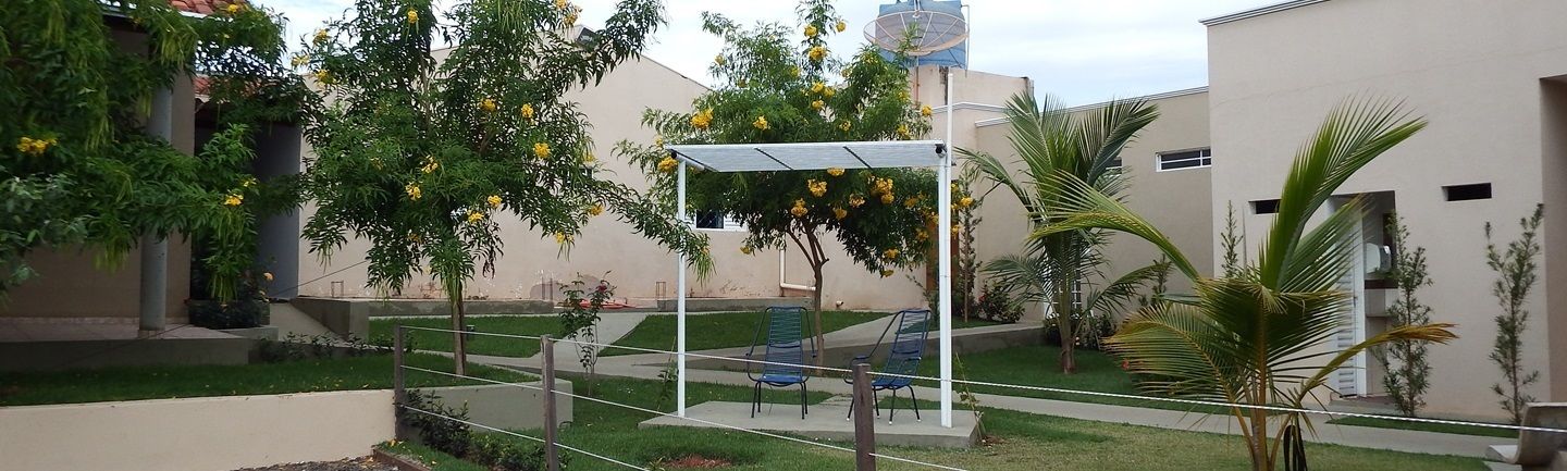 A courtyard with a covered seating area, palm trees, and a building with a water tank in the background.