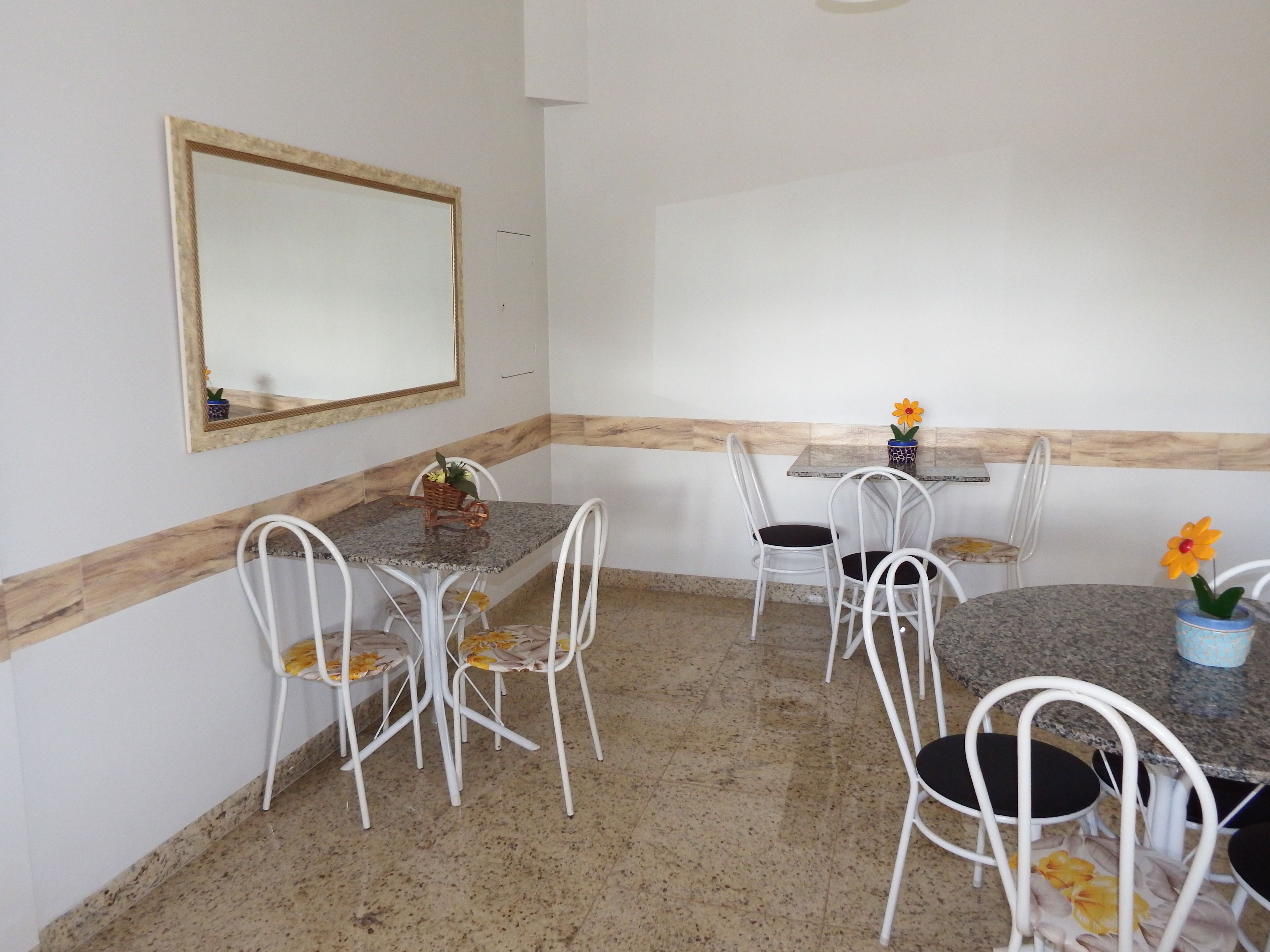 Un comedor con una mesa de mármol, sillas blancas y un espejo en la pared.