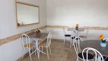 Un comedor con una mesa de mármol, sillas blancas y un espejo en la pared.