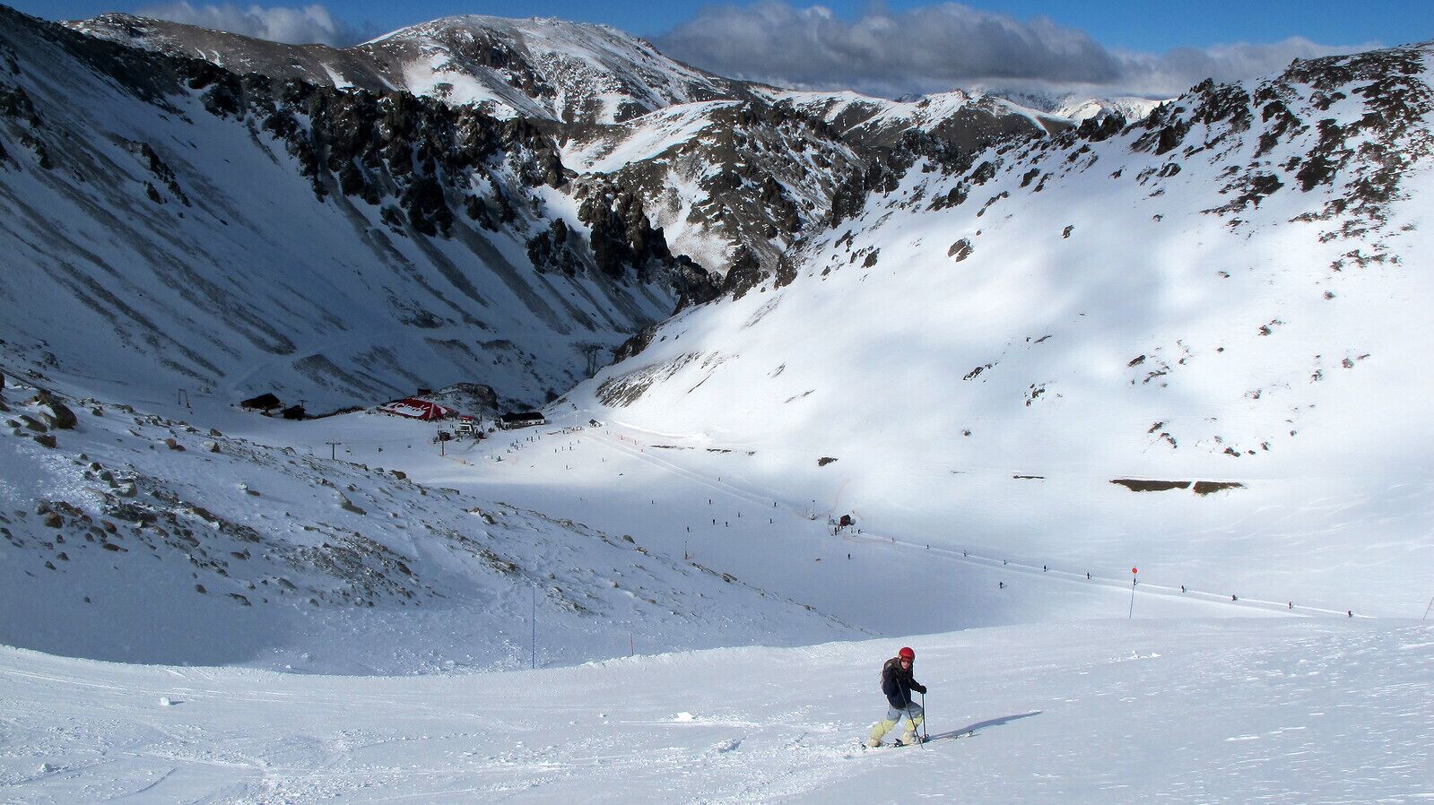 Une pente de montagne enneigée, avec un seul skieur.